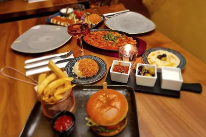 A hearty burger with chips, rice, and a selection of dips – perfect for a satisfying meal at Inco Turkish Restaurant & Fish Bar in Romford.