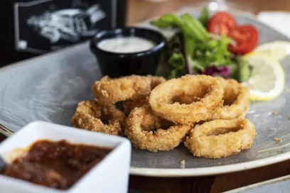 Crispy fried calamari served with a fresh salad and dipping sauce, a perfect starter at Inco Turkish Restaurant & Fish Bar in Romford.